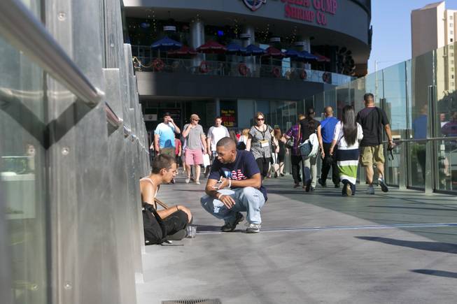 Marcus Mitchell, a local Las Vegas gambler who donates a majority of his winnings to those in need, converses with a young homeless man on a pedestrian bridge crossing the Strip, Tuesday Aug. 13, 2013. Since the passing of his wife in 2008, Marcus has been finding ways to randomly help people he comes in contact with, either in person or online.